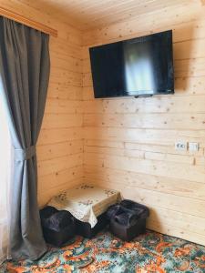een kamer met een tv aan de muur met twee poeven bij Вершина Карпат in Krasnik