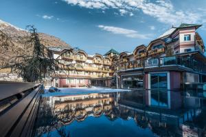 un edificio con una piscina d'acqua di fronte ad esso di Tevini Dolomites Charming Hotel a Commezzadura