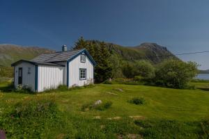 een klein wit huis in een grasveld bij Cozy cabin with stunning view in Alstad