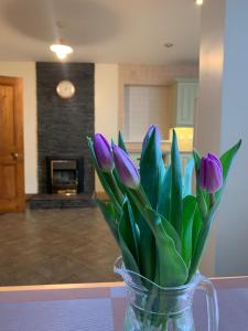 un jarrón de tulipanes púrpuras sentado en una mesa en Ringfort Manor, en Rathfriland
