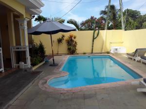 uma piscina com um guarda-sol ao lado de uma casa em Appartement de vacances em Grand Baie