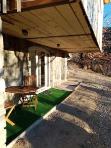 a porch with a table and a bench on a green lawn at Studio de Charme neuf à la Montagne in Puget-Rostang +11 photos