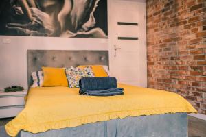 a bedroom with a yellow bed with a brick wall at Silver box in Gdańsk