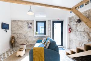 a living room with a blue couch and a stone wall at GuestReady - The New Pateo da Lapa - Casa 3 in Porto