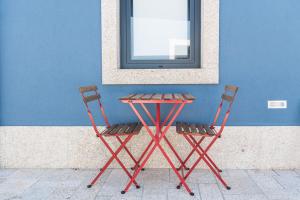 a red table and two chairs next to a blue wall at GuestReady - The New Pateo da Lapa - Casa 3 in Porto