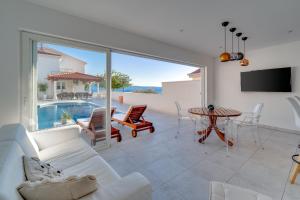 ein Wohnzimmer mit einer weißen Couch und einem Tisch in der Unterkunft Seaview Villa MaToLi with heated 50sqm pool and 4 bedrooms, close to Split in Podstrana