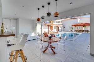 ein Esszimmer mit einem Tisch, Stühlen und einem Pool in der Unterkunft Seaview Villa MaToLi with heated 50sqm pool and 4 bedrooms, close to Split in Podstrana