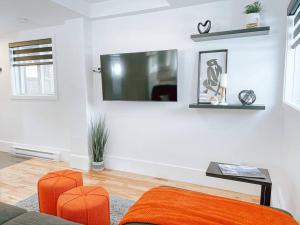 uma sala de estar com cadeiras laranja e uma televisão na parede em Complexe LIVTremblant by Gestion ELITE - LIV5 em Mont-Tremblant