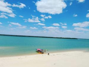 a boat sitting on a beach in the water at Pousada Pôr do Sol - Galinhos in Galinhos