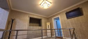 a room with a staircase with a television and a stair railing at Sheykh hostel in Andizhan