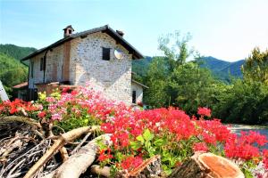 an old stone house with flowers in front of it at Agriturismo Malvista in San Sebastiano Curone