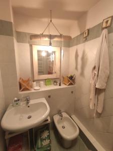 ein weißes Badezimmer mit einem Waschbecken und einem Spiegel in der Unterkunft Sotto Sotto in Viareggio