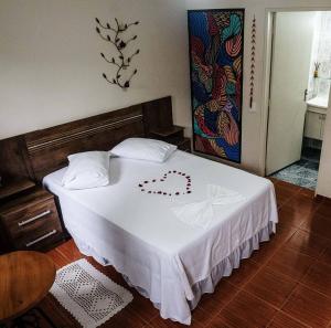 a bedroom with a white bed with a heart on it at Recanto Toca das Plantas de Ilhabela I in Ilhabela