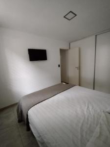 1 dormitorio con 1 cama y TV en la pared en Necochea Isor en Godoy Cruz