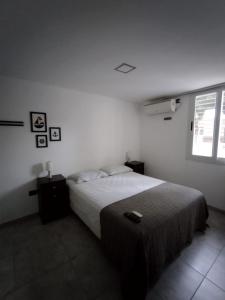 a white bedroom with a bed and a window at Necochea Isor in Godoy Cruz