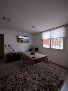 sala de estar con mesa y TV en la pared en Necochea Isor en Godoy Cruz