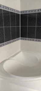 a white bath tub in a bathroom with black tiles at Spacious apartment at the foot of Mashuk mountain in Pyatigorsk
