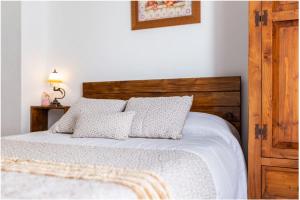 Un dormitorio con una cama blanca con cabecero de madera. en APARTAMENTO EN OLVERA CON GARAJE, en Olvera 37 fotos más