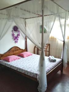 a bedroom with a canopy bed with pink pillows at location weligama in Weligama