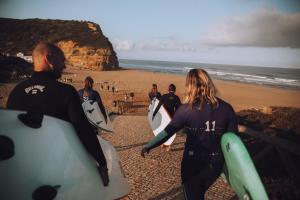 a group of people walking on the beach with surfboards at João Jungle in Açafora