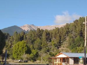 a house with trees and mountains in the background at Don Edmundo Trevelin in Trevelín