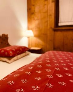 a bed with a red blanket with white flowers on it at Appartamenti Pichler in Castello di Fiemme