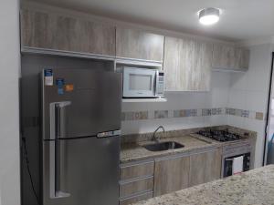 a kitchen with a stainless steel refrigerator and a microwave at Apartamento Moderno Poços de Caldas in Poços de Caldas