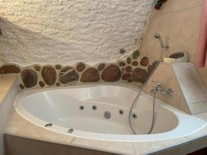 a bath tub in a bathroom with a shower at Casa Job - Gasthaus - Sauna, Whirlpool - Trun in Trun