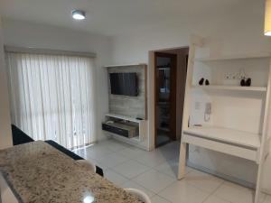 sala de estar con mesa y TV en Apartamento Moderno Poços de Caldas, en Poços de Caldas