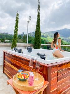 a woman in a bath tub with a bowl of fruit and wine glasses at Hotel Boutique Palmas de Salento in Salento
