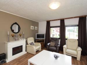 ein Wohnzimmer mit einem Kamin, Stühlen und einem TV in der Unterkunft Spacious holiday home in the Ore Mountains in Deutschneudorf