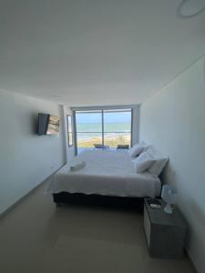 biała sypialnia z łóżkiem i dużym oknem w obiekcie Vista mar!! w mieście Cartagena de Indias