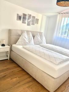 ein weißes Bett in einem Zimmer mit Fenster in der Unterkunft Ena Appartements in Altenmarkt im Pongau