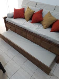 um sofá de madeira com almofadas no topo de um piso em Departamento Anita centro em Maipú
