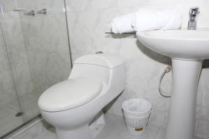 a white bathroom with a toilet and a sink at Hotel Dorado Plaza Bogota in Bogotá