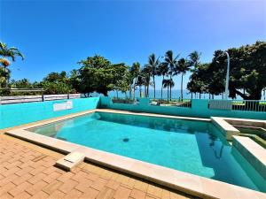 a swimming pool with palm trees in the background at Emthree Seaside Apartments in Townsville