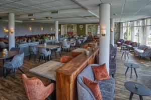 a restaurant with tables and chairs and a bar at Landgoed Hotel Tatenhove Texel in De Koog