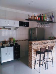 a kitchen with two bar stools and a counter at Casa Inteira aconchegante com garagem Próximo ao Aeroporto in Lauro de Freitas