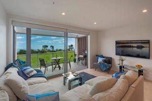 a living room with a couch and a large window at Tahunanui Oceanview Apartment in Nelson