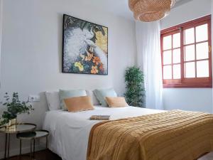 1 dormitorio con 1 cama con una pintura en la pared en Misterhost Santa Cruz II -Jardines de Murillo, en Sevilla