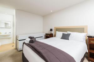 a bedroom with a large white bed and a sink at Silver Sands - Beachside Apartment in Nelson