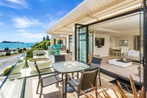 a house with a balcony with a table and chairs at Silver Sands - Beachside Apartment in Nelson
