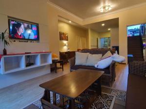 een woonkamer met een bank en een tv bij Gerard's Place Nature Haven Apartment in Tanah Rata