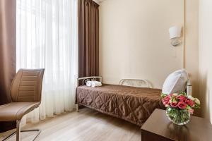 モスクワにあるHotel Andreevskiyのベッドと花のテーブルが備わるホテルルームです。