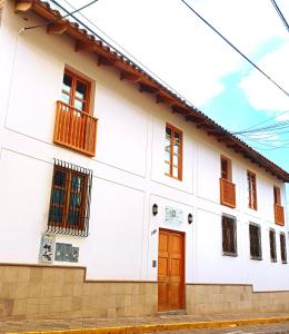 un edificio blanco con una puerta y ventanas marrones en 7th Wonder Apart Hotel Cusco, en Cusco
