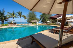 高蘭的住宿－Gooddays Lanta Beach Resort SHA，一个带两把椅子和遮阳伞的游泳池