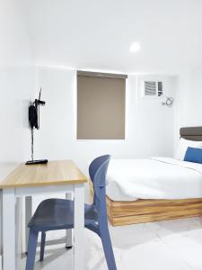 a bedroom with a bed and a table and a chair at airobedz MAKATI - A Value Hotel in Manila