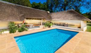 a thatch roofed house with a swimming pool at Pine Valley in Lanseria