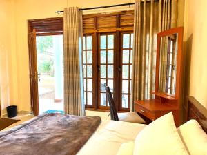a bedroom with a bed and a desk and a window at Hotel mango tree nearest Adam's peak in Nallathanniya