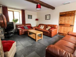 a living room with leather couches and a coffee table at Maestyddyn Farm House in Clocaenog